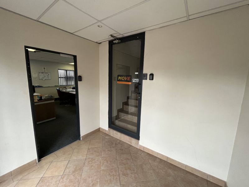 A functional office entry area featuring tiled flooring, a suspended ceiling, and secure glass door access with integrated keypad entry systems.