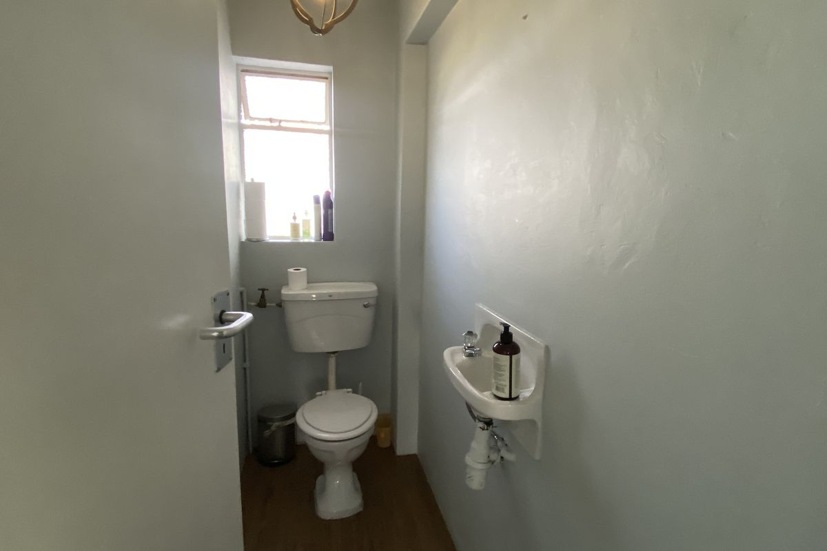A compact office restroom featuring a standard toilet and a wall-mounted basin with functional plumbing fixtures.