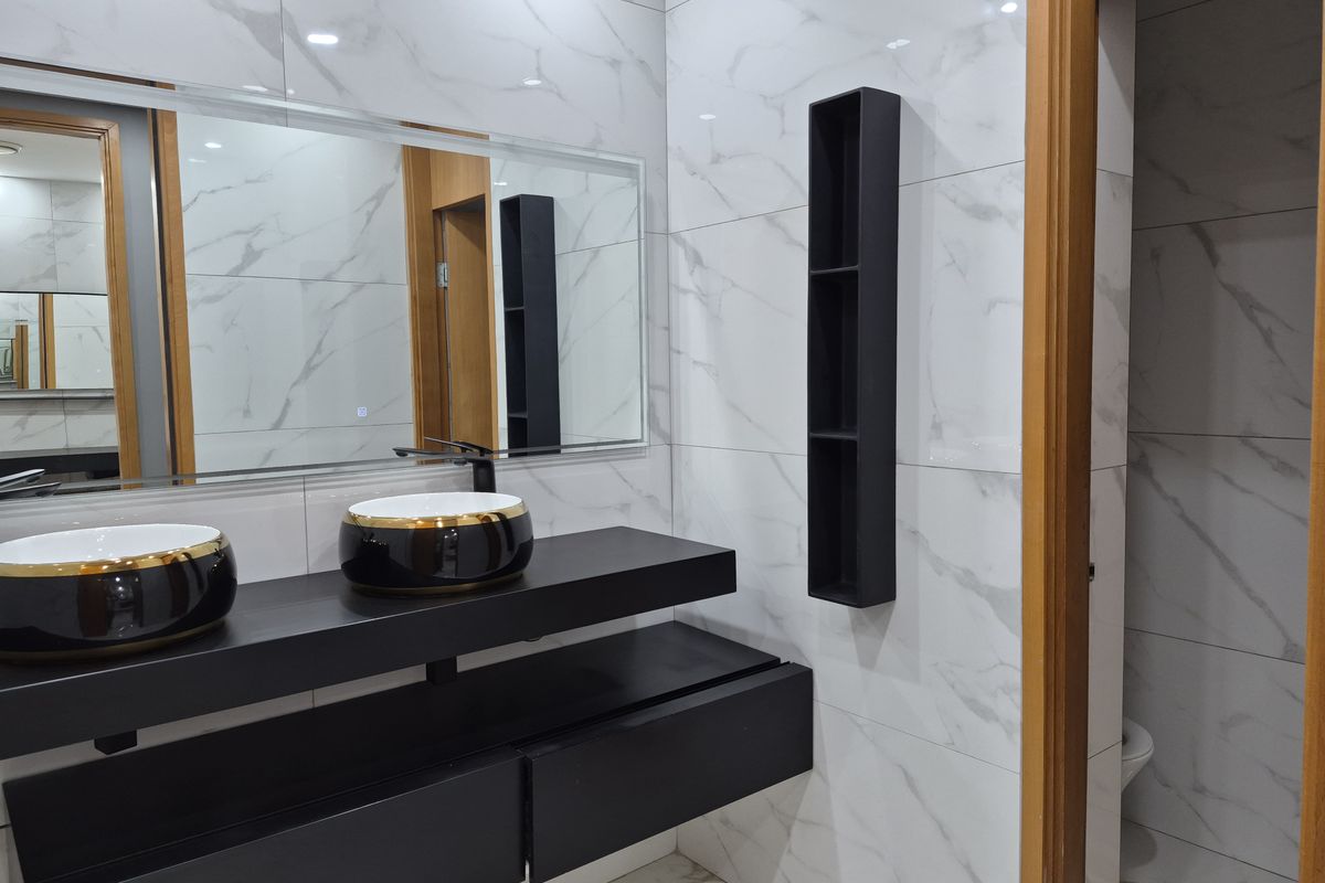 Modern bathroom featuring a sleek double vanity with vessel sinks, large wall mirror, and elegant marble-effect wall tiling.