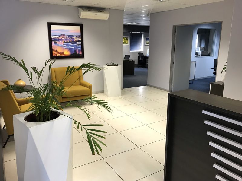 A professional office reception area featuring tiled flooring, a built-in reception desk, and a split-system air conditioning unit.
