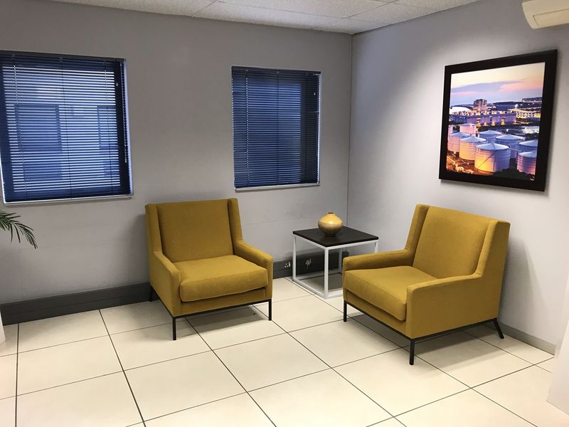 A professional office waiting area featuring tiled flooring, neutral walls, and dual windows with fitted venetian blinds.