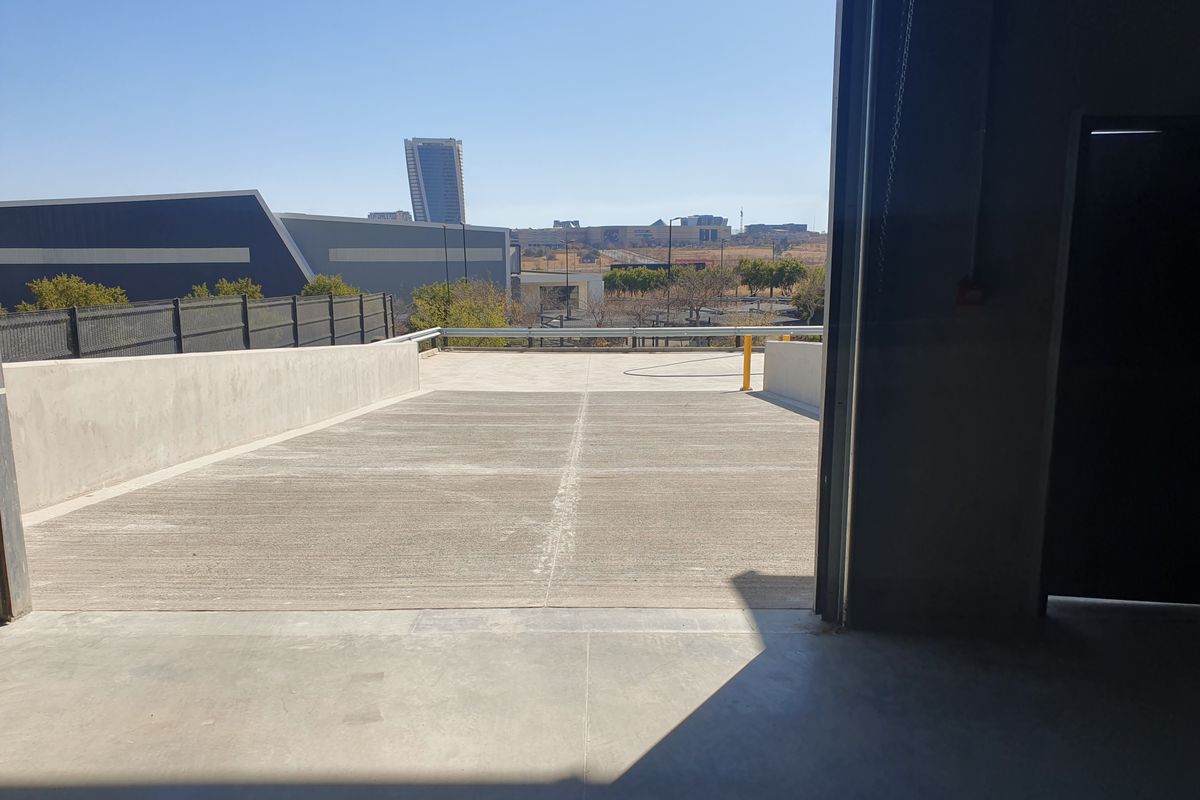 View from an industrial unit looking out onto a concrete loading ramp and paved yard area with surrounding commercial buildings.