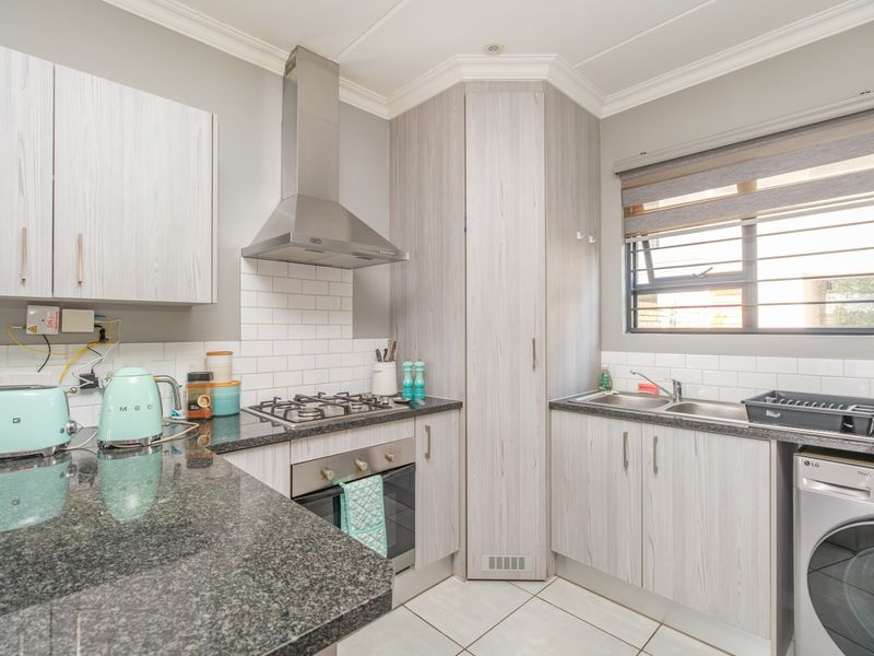 Modern kitchen featuring granite countertops, subway tile backsplash, built-in oven, gas hob, stainless steel extractor fan, and ample built-in cabinetry.