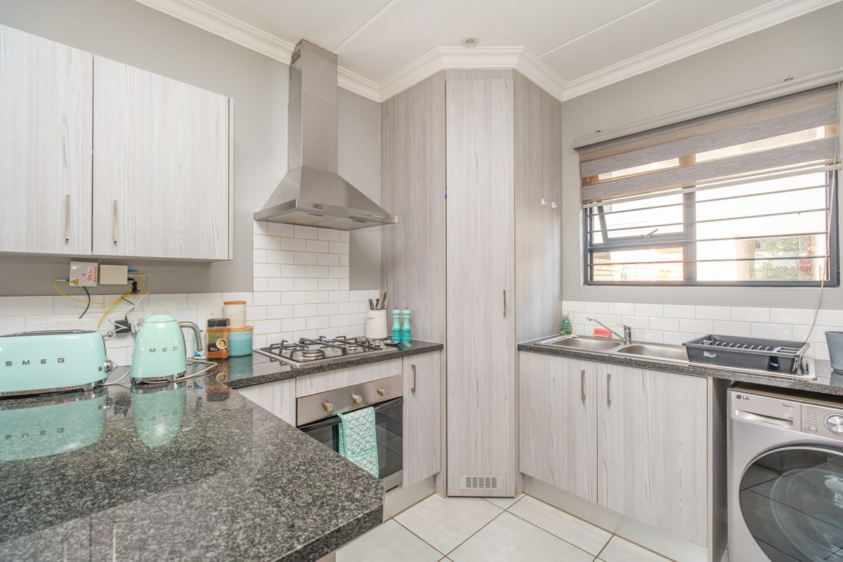 Modern kitchen featuring granite countertops, subway tile backsplash, built-in oven, gas hob, stainless steel extractor fan, and ample built-in cabinetry.