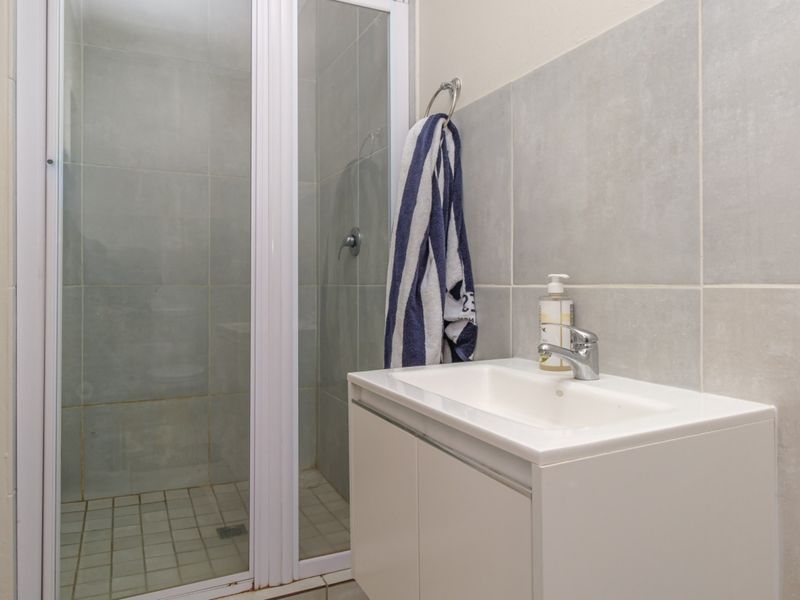 A functional bathroom featuring a shower enclosure with a glass door and a modern white vanity cabinet with a basin.