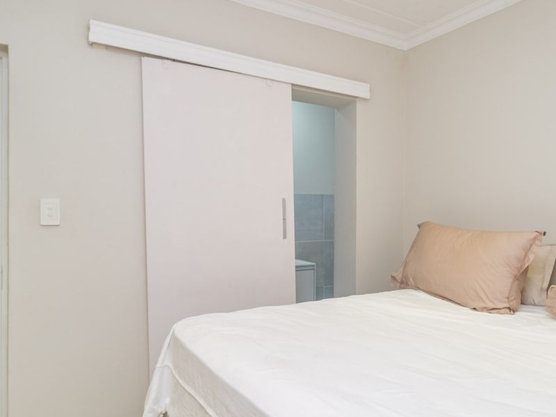 A bedroom featuring neutral walls, crown molding, and a sliding door providing access to an adjacent space.