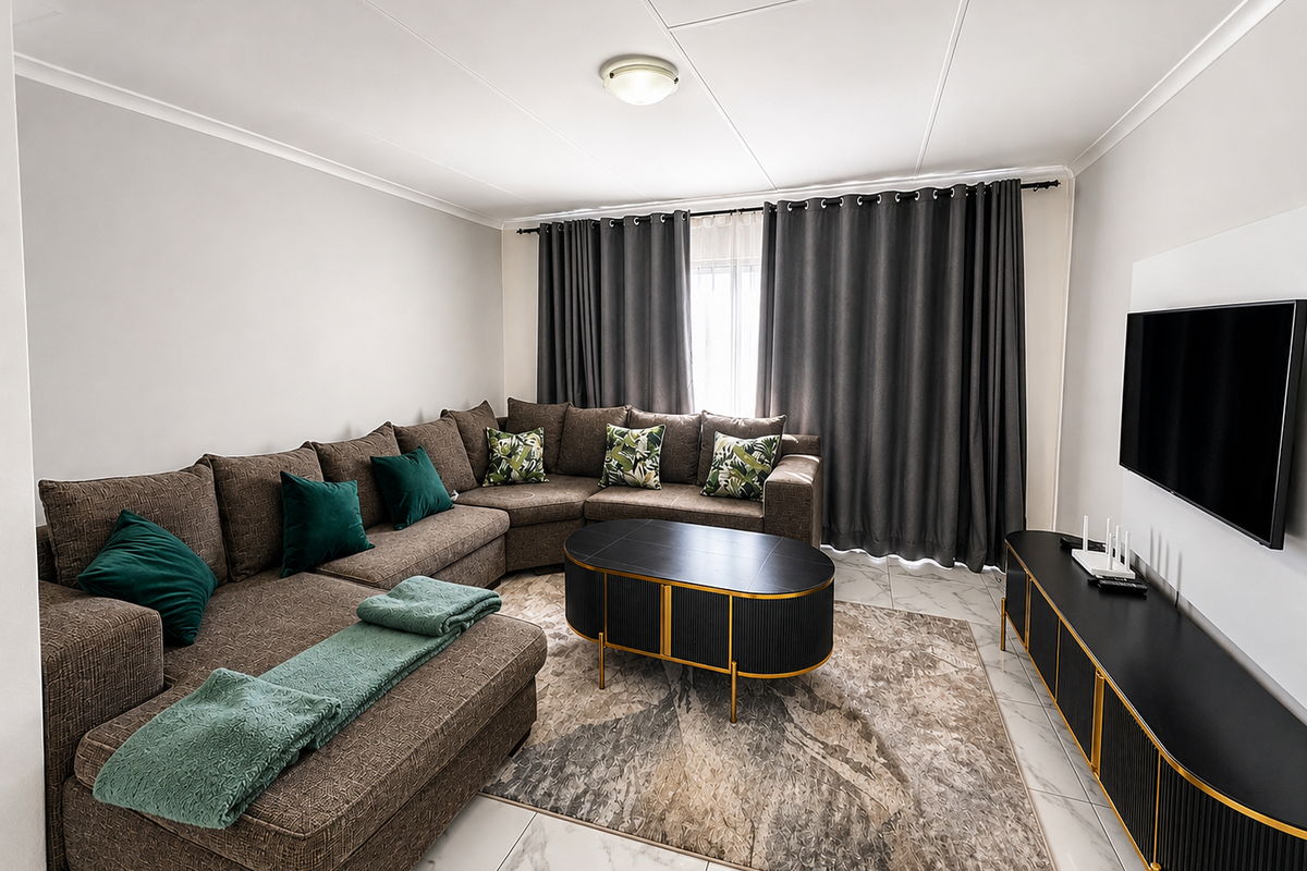 A well-maintained living room featuring large format marble-look floor tiles, neutral wall finishes, and integrated curtain tracks for window treatments.