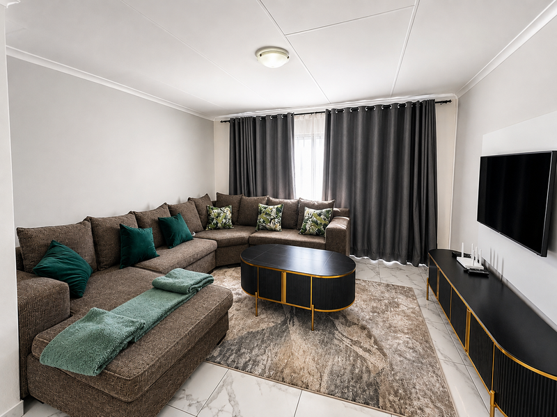 A well-maintained living room featuring large format marble-look floor tiles, neutral wall finishes, and integrated curtain tracks for window treatments.