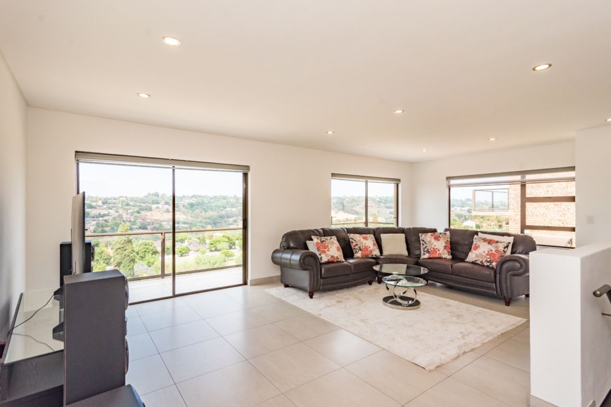 Spacious living room featuring large sliding glass doors with scenic views, neutral tiled flooring, and recessed downlighting.
