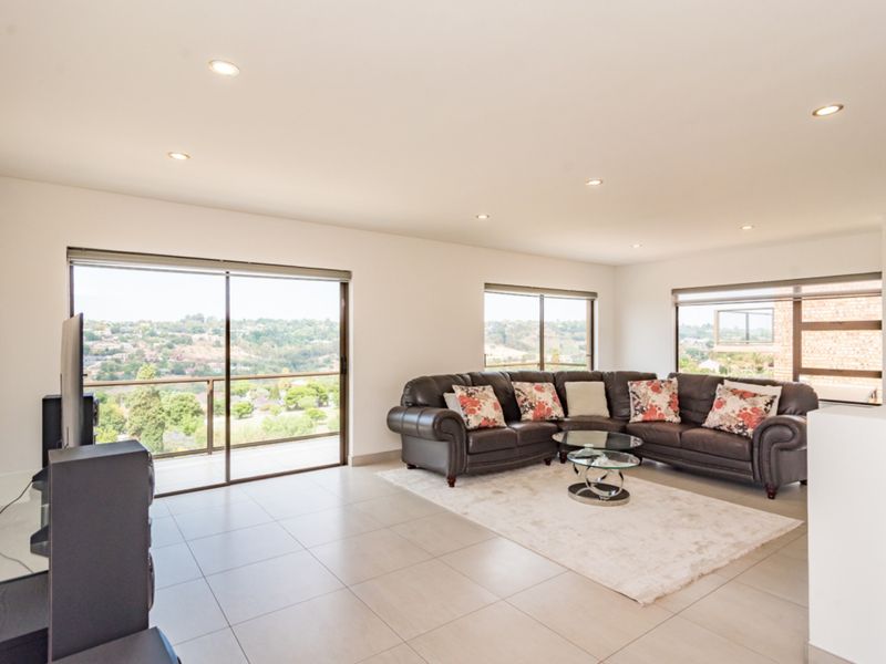 Spacious living room featuring large sliding glass doors with scenic views, neutral tiled flooring, and recessed downlighting.