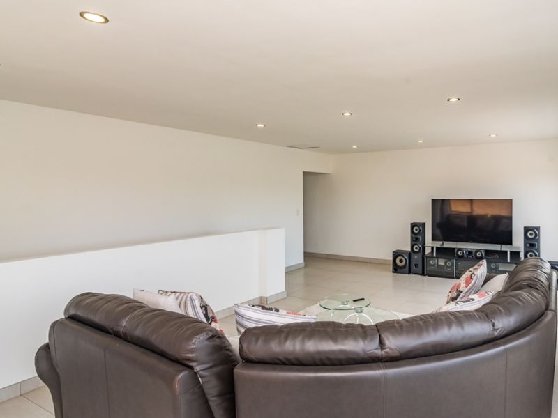 Spacious living area featuring neutral tiled flooring, recessed downlighting, and a modern half-height partition wall, creating an open and bright atmosphere.