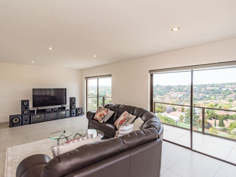 Spacious living room featuring large sliding glass doors that open to a balcony with expansive elevated views and modern tiled flooring.
