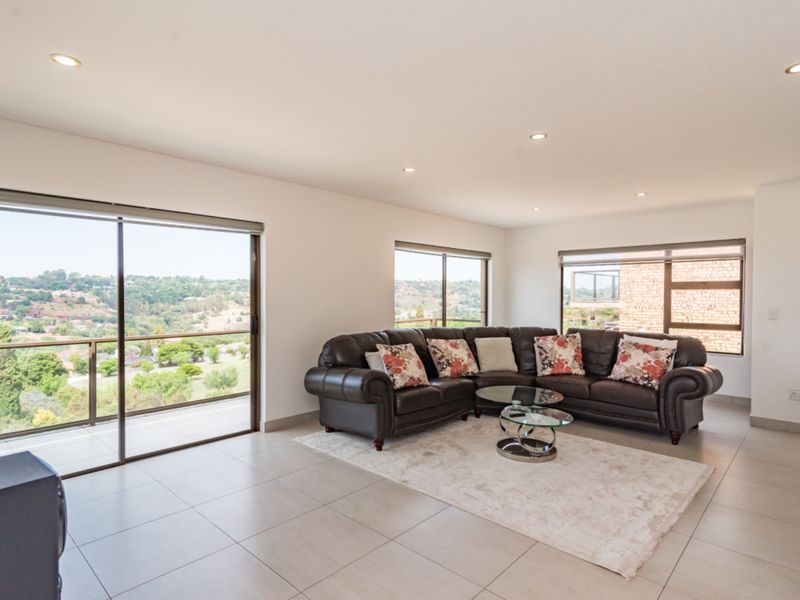Spacious living room featuring large sliding glass doors, neutral tiled flooring, recessed downlights, and expansive views of the surrounding landscape.