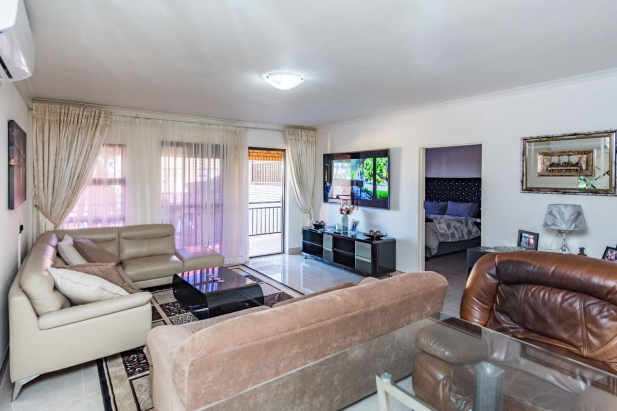A spacious living room featuring tiled flooring, an air conditioning unit, and a sliding glass door leading to an outdoor balcony area.