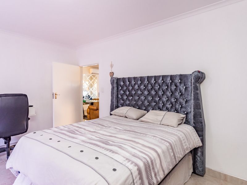 A well-maintained bedroom featuring neutral tiled flooring and coved ceiling details, offering a clean and functional living space.