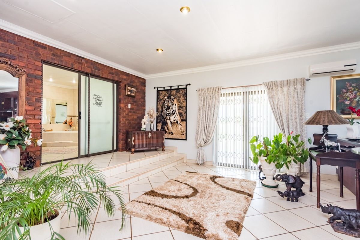 Spacious living area featuring tiled flooring, a distinctive exposed brick feature wall, and sliding glass doors leading to an outdoor space.