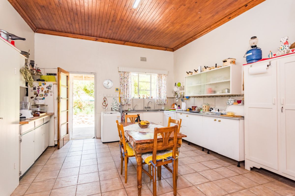 A functional kitchen featuring tiled flooring, timber ceiling, and built-in cabinetry with direct access to the outdoor area.