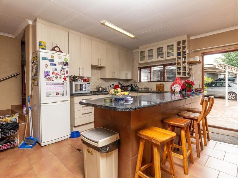 Functional kitchen featuring light-toned cabinetry, granite countertops, a central island with breakfast bar seating, and direct access to the exterior.