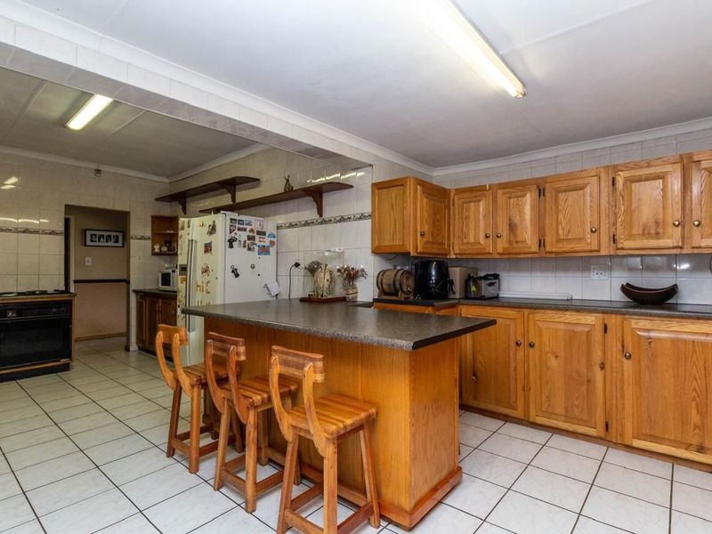Spacious kitchen featuring wooden cabinetry, a central island with breakfast bar seating, tiled flooring, and a tiled backsplash.