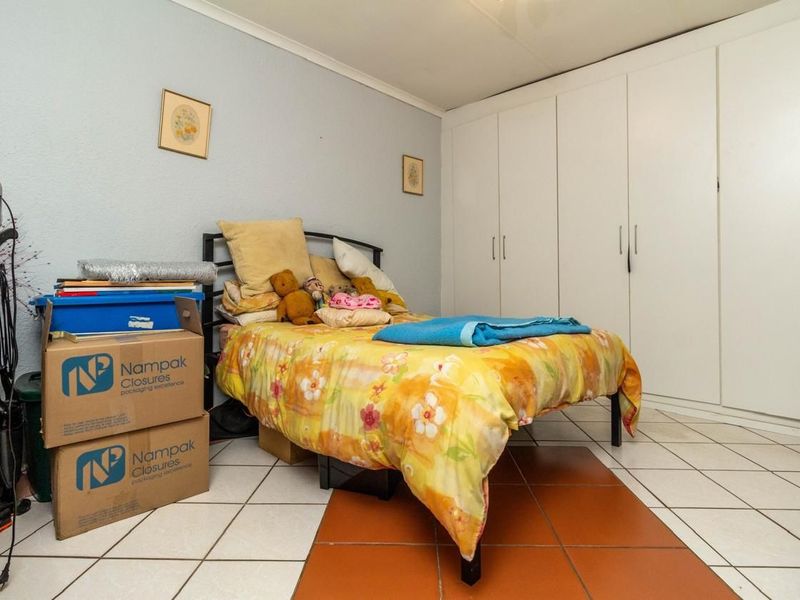 A bedroom featuring built-in cupboards and tiled flooring, offering a functional space with potential for modernization.