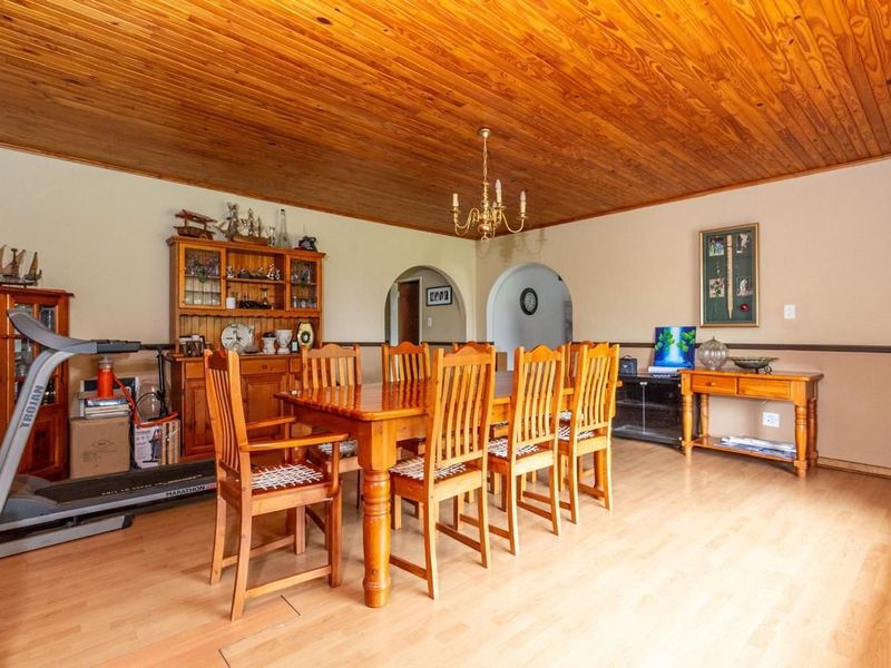 Spacious dining room featuring a warm wooden ceiling, laminate flooring, and classic archway transitions to adjacent living areas.