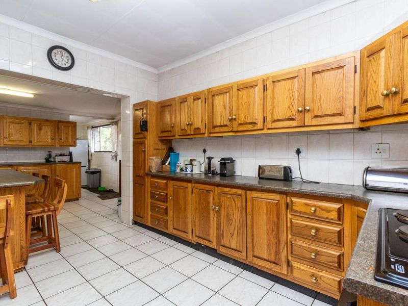 A functional kitchen featuring traditional wooden cabinetry, tiled flooring, and a breakfast nook, offering a classic layout with ample storage space.