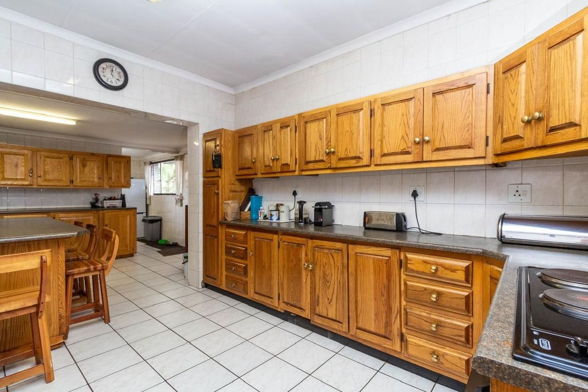 A functional kitchen featuring traditional wooden cabinetry, tiled flooring, and a breakfast nook, offering a classic layout with ample storage space.