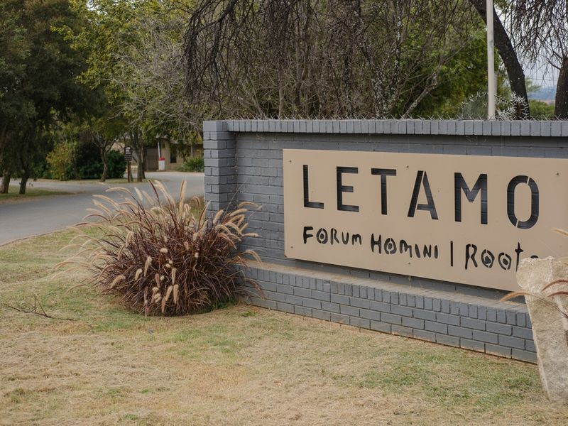 Entrance signage for Letamo estate featuring a brick boundary wall and established landscaping along the access road.