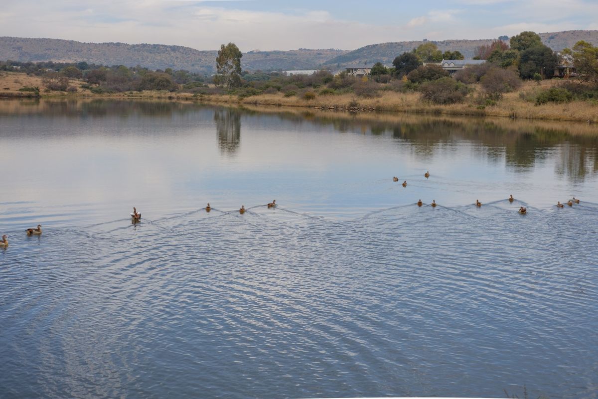 A scenic view of a tranquil lake surrounded by natural landscape and rolling hills, offering a peaceful outlook for the property.