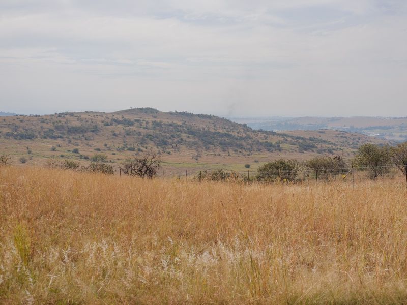 A scenic view of the surrounding hilly landscape and natural vegetation, featuring a wire boundary fence.