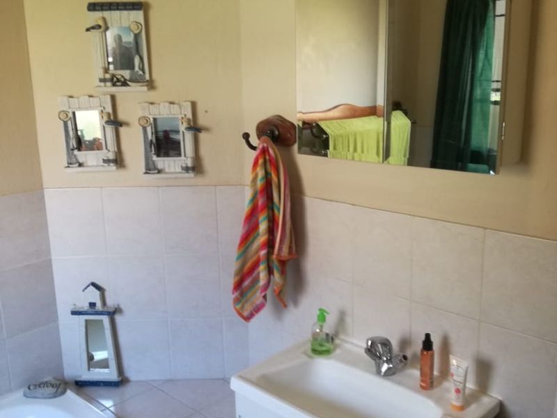 A functional bathroom featuring a vanity with basin, mirrored medicine cabinet, and a tiled built-in bathtub.