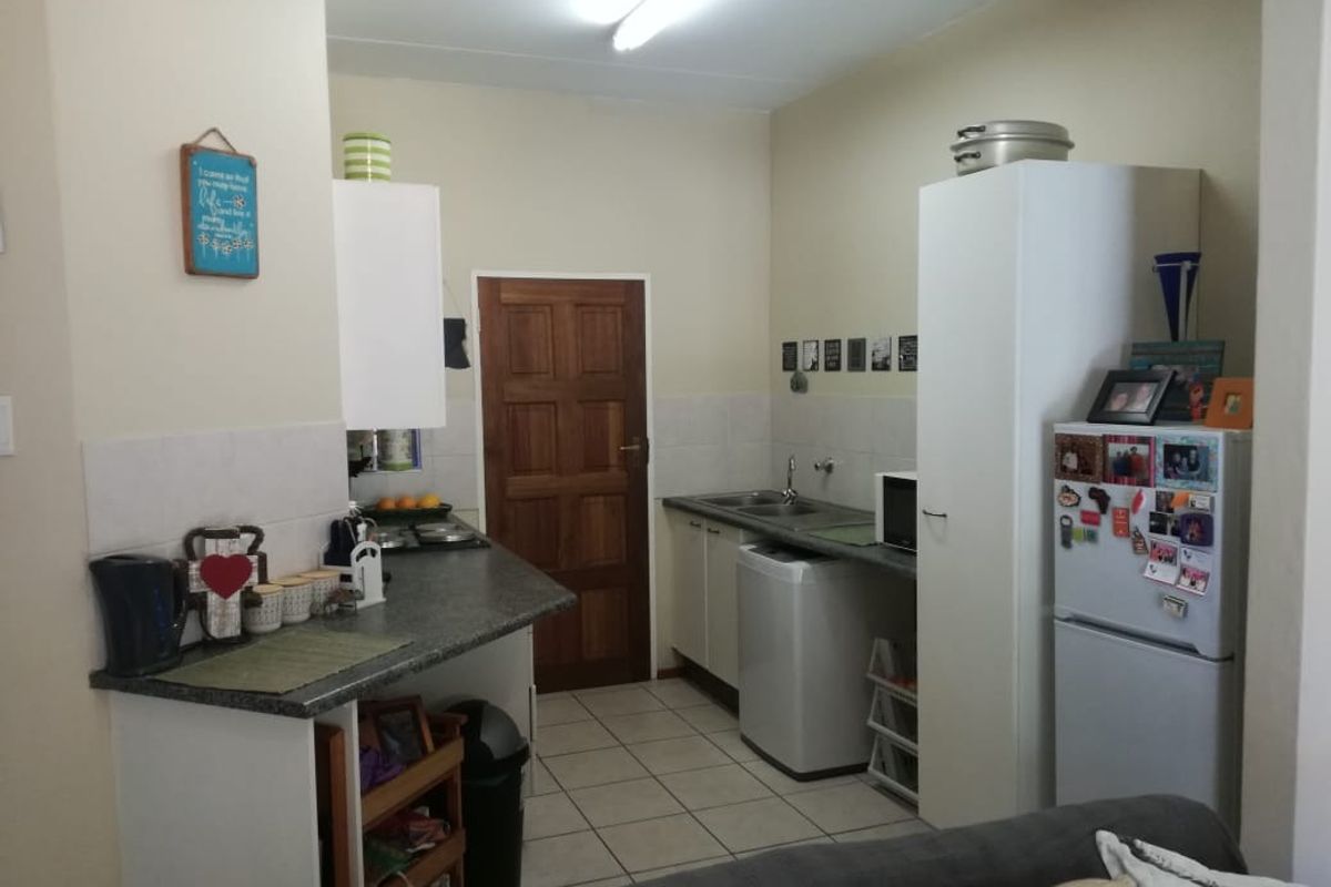 A functional kitchen featuring tiled flooring, laminate countertops, built-in cabinetry, and a stainless steel sink, offering a practical layout for daily use.