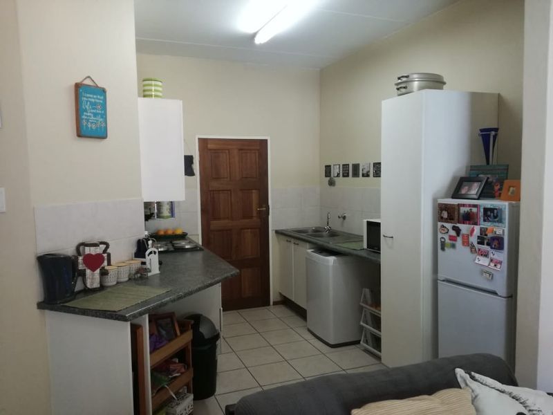 A functional kitchen featuring tiled flooring, laminate countertops, built-in cabinetry, and a stainless steel sink, offering a practical layout for daily use.
