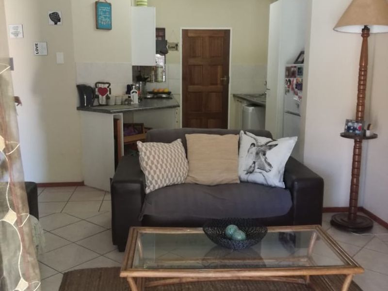 An open-plan living area featuring tiled flooring and a compact kitchen space with built-in cabinetry and countertops.