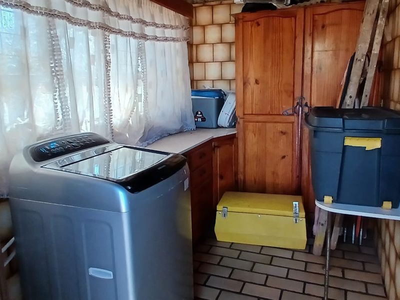 A functional laundry area featuring built-in wooden cabinetry, tiled walls, and tiled flooring, providing a practical space for utility and storage needs.