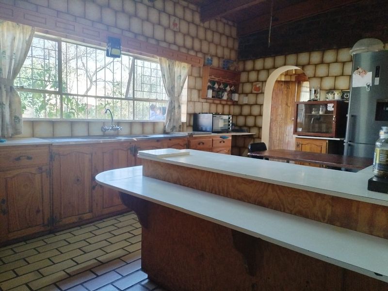 A rustic kitchen featuring wooden cabinetry, a breakfast bar, and tiled backsplash, offering a traditional layout with potential for modern updates.