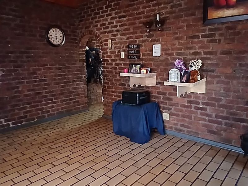 Living area featuring rustic exposed brick walls, tiled flooring, and distinctive arched doorways leading to adjacent spaces.