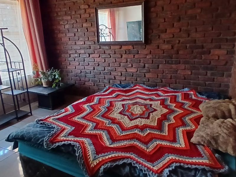 A bedroom featuring exposed brick walls and tiled flooring, providing a rustic aesthetic with natural light from a large window.