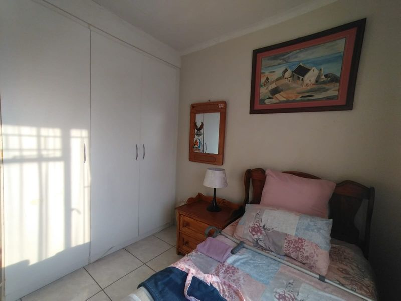 A functional bedroom featuring built-in cupboards and tiled flooring, offering a neutral space ready for personalization.