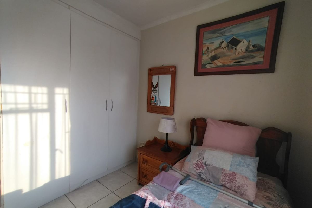 A functional bedroom featuring built-in cupboards and tiled flooring, offering a neutral space ready for personalization.