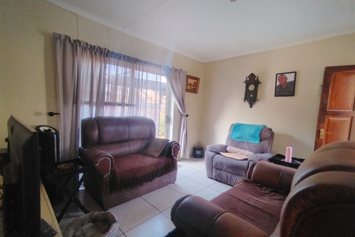 A living room featuring tiled flooring and a sliding glass door providing natural light.
