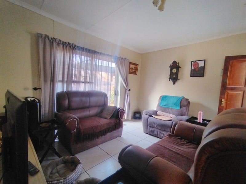 A living room featuring tiled flooring and a sliding glass door providing natural light.