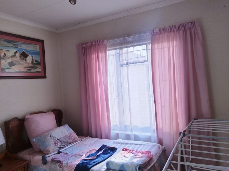A standard bedroom featuring a window with security bars and neutral wall finishes.