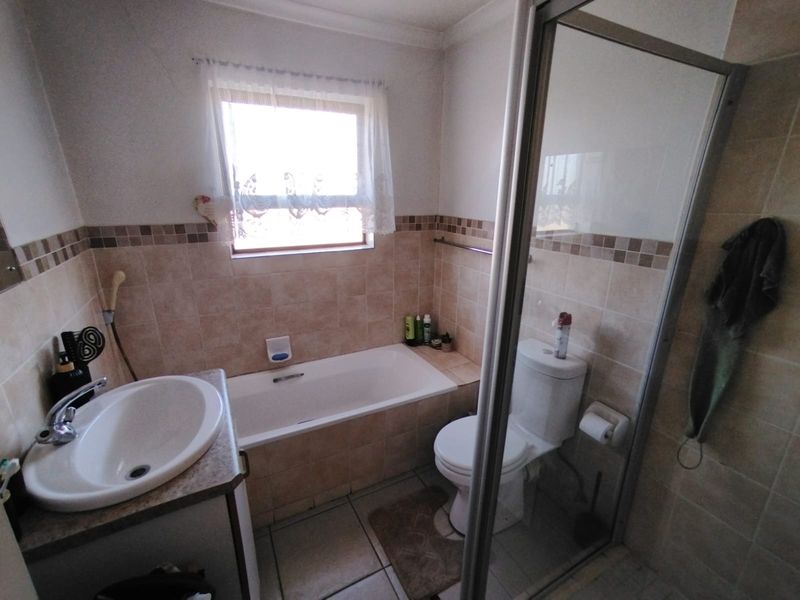 A functional bathroom featuring a built-in vanity with basin, a bathtub, a separate shower enclosure, and tiled finishes throughout.