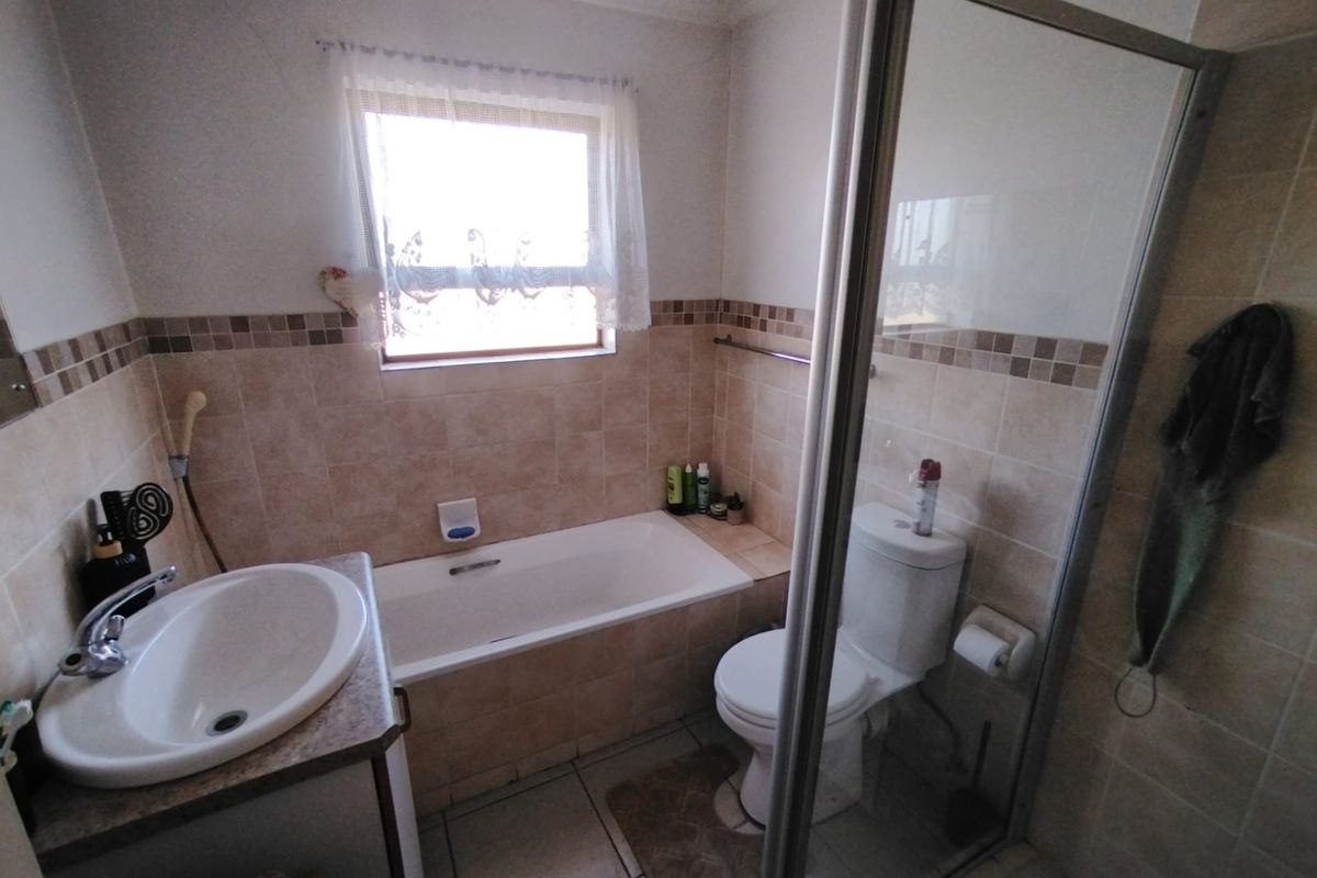 A functional bathroom featuring a built-in vanity with basin, a bathtub, a separate shower enclosure, and tiled finishes throughout.