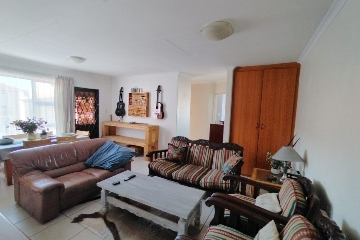 A spacious living area featuring tiled flooring and a built-in storage cupboard, offering a functional layout with access to adjacent rooms.