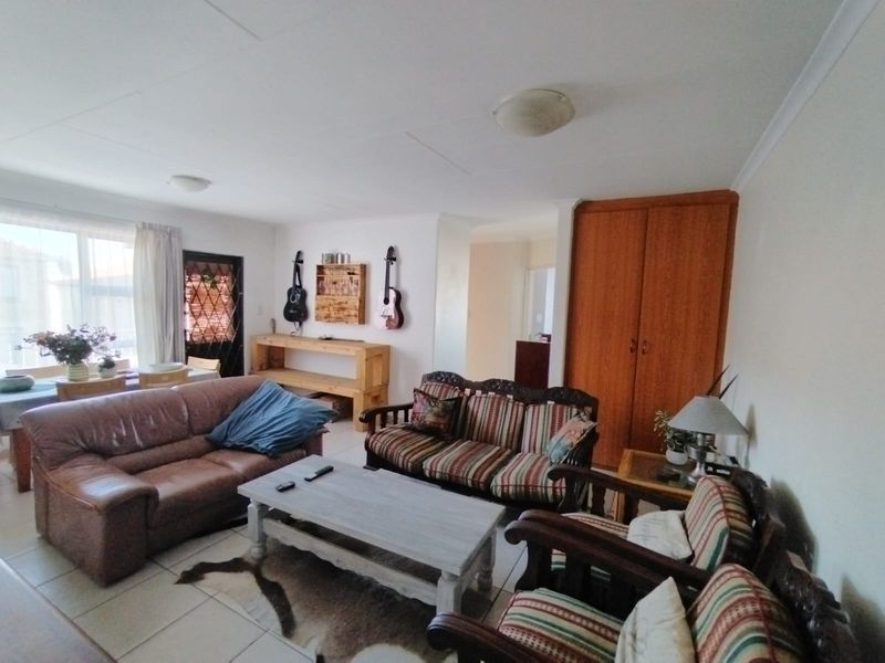 A spacious living area featuring tiled flooring and a built-in storage cupboard, offering a functional layout with access to adjacent rooms.