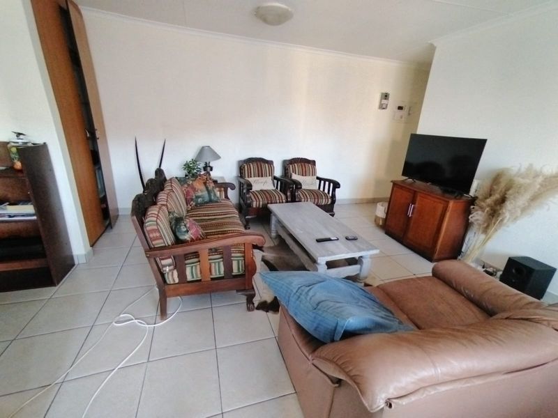 A living room area featuring tiled flooring and a built-in storage cupboard, providing a functional space for relaxation.