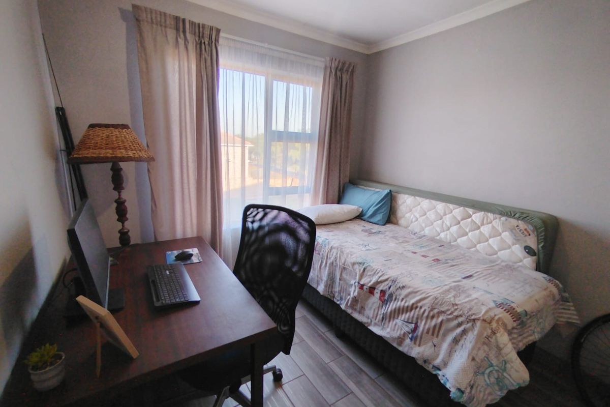 A functional bedroom featuring tiled flooring, neutral wall finishes, and a large window providing natural light.