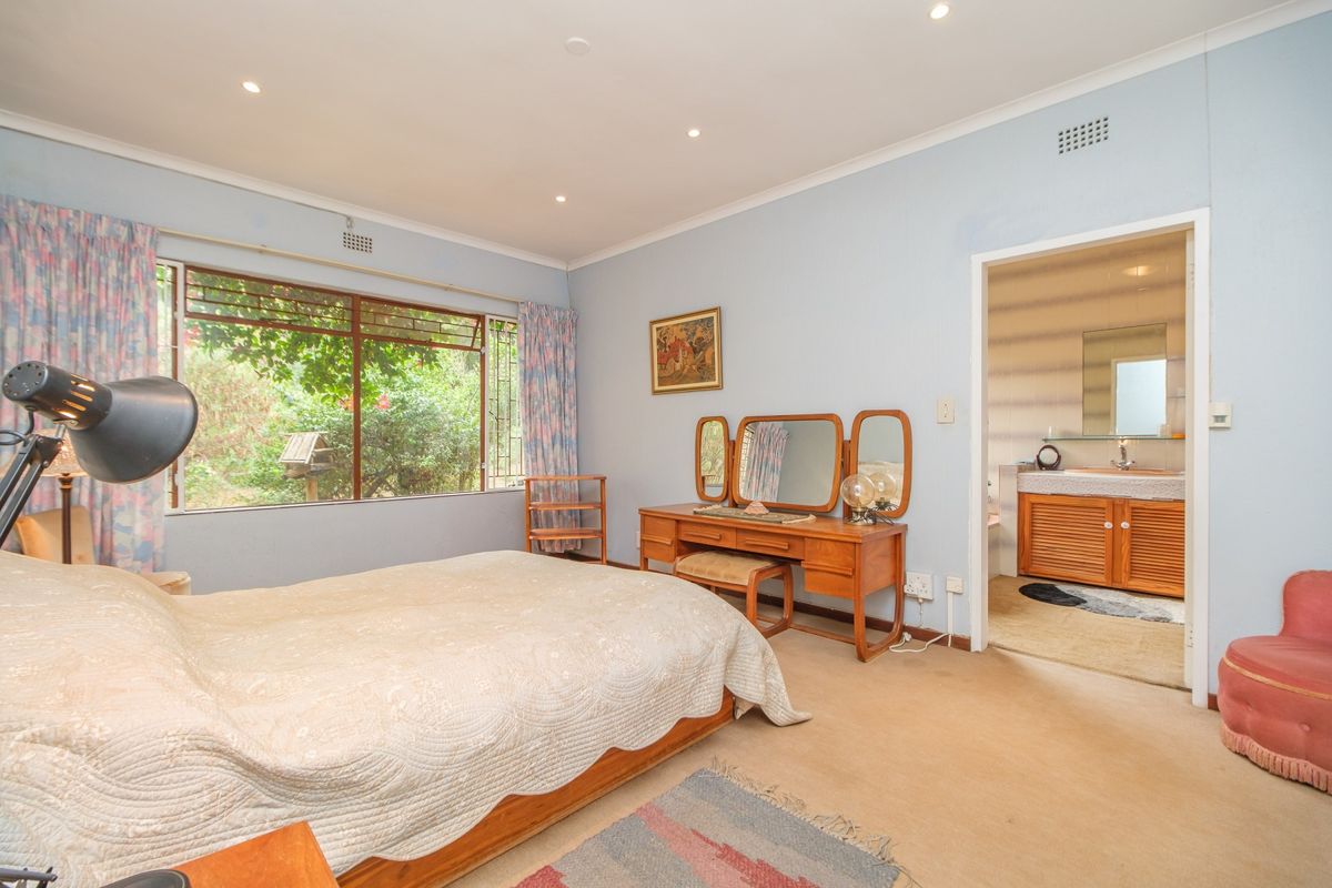 Spacious bedroom featuring carpeted flooring, recessed downlights, and an adjoining en-suite bathroom with vanity cabinetry.